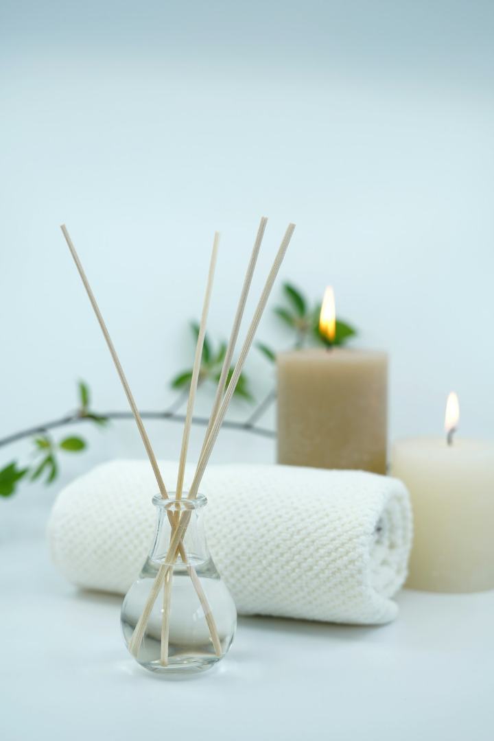 Bougies allumées, serviette écrue roulée et branche de feuillage dans une lumière douce