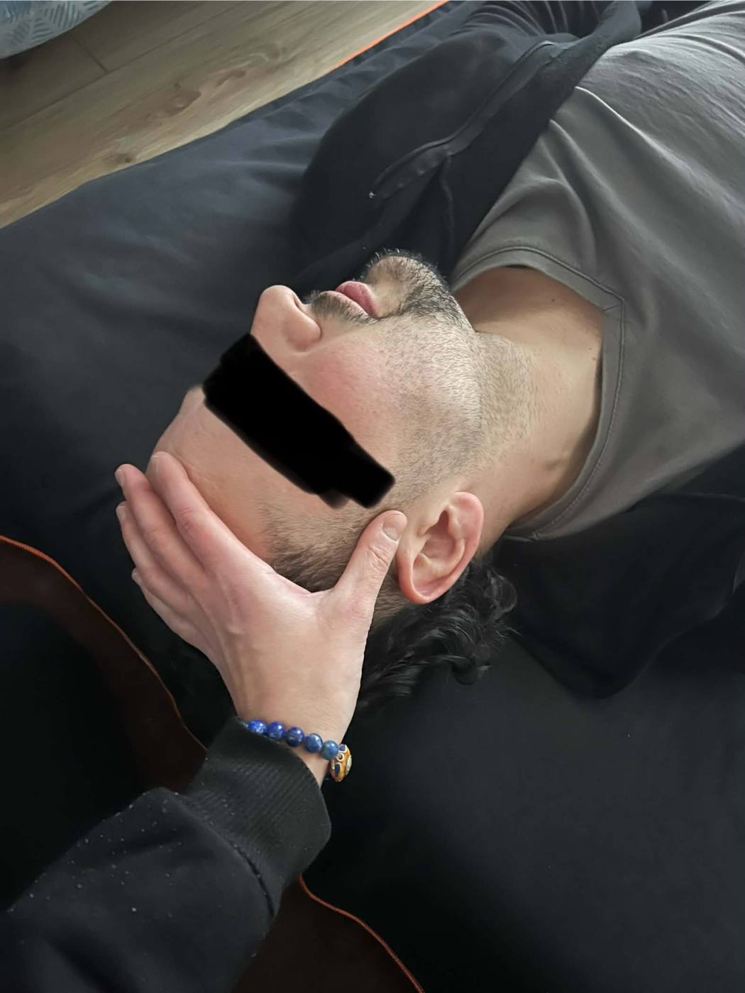 Les mains de Myriam soutenant la tête d'une personne allongée, pendant un soin crânien