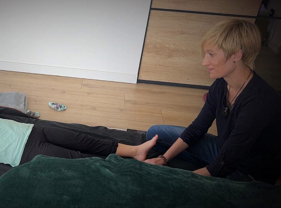Myriam Blanc, assise au sol, les mains posées sur le pied d'un enfant allongé sous une couverture