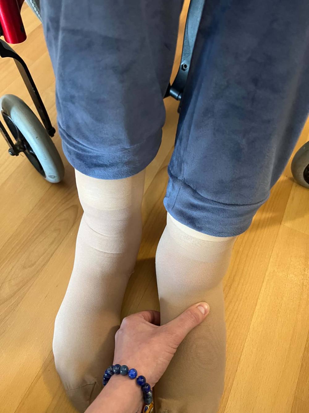 La main de Myriam posée sur la jambe d'une personne, lors d'un soin à domicile